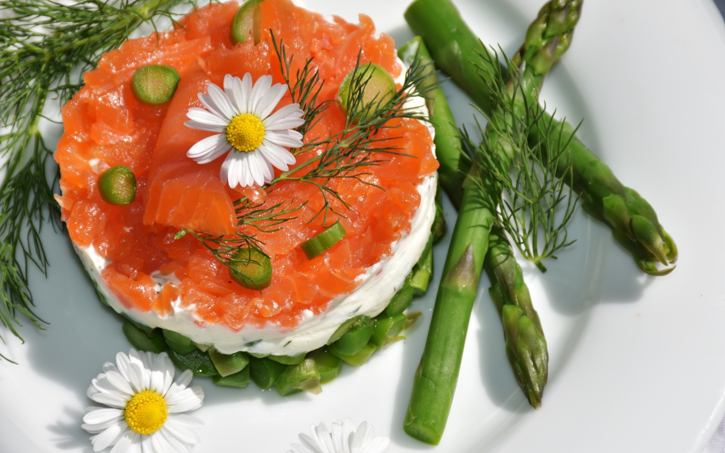 Салат с красной рыбой на тарелке со спаржей, укропом и цветами ромашки