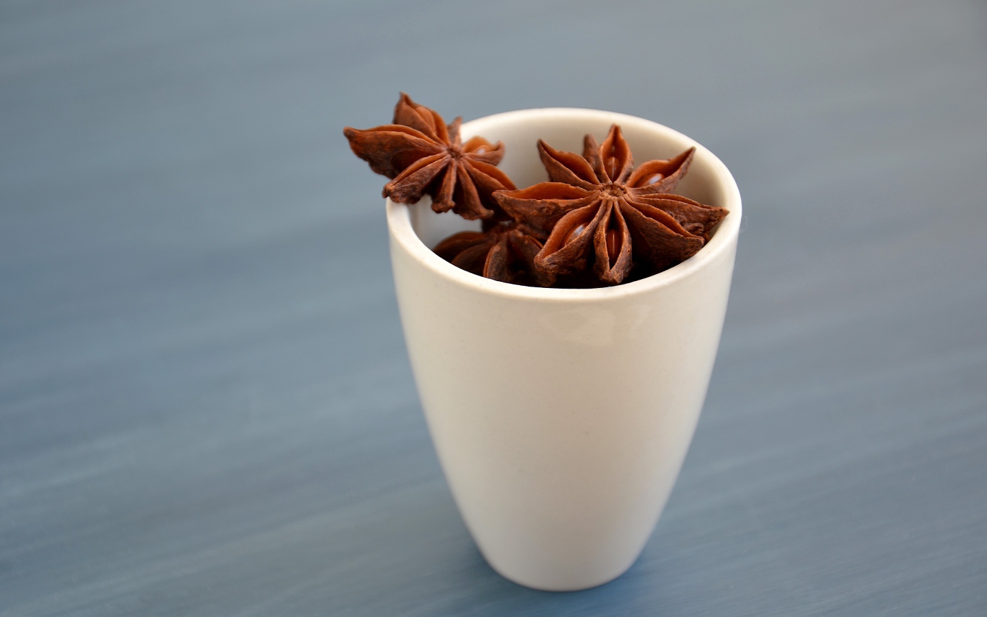 Звездочки бадьяна в белой чашке на столе 