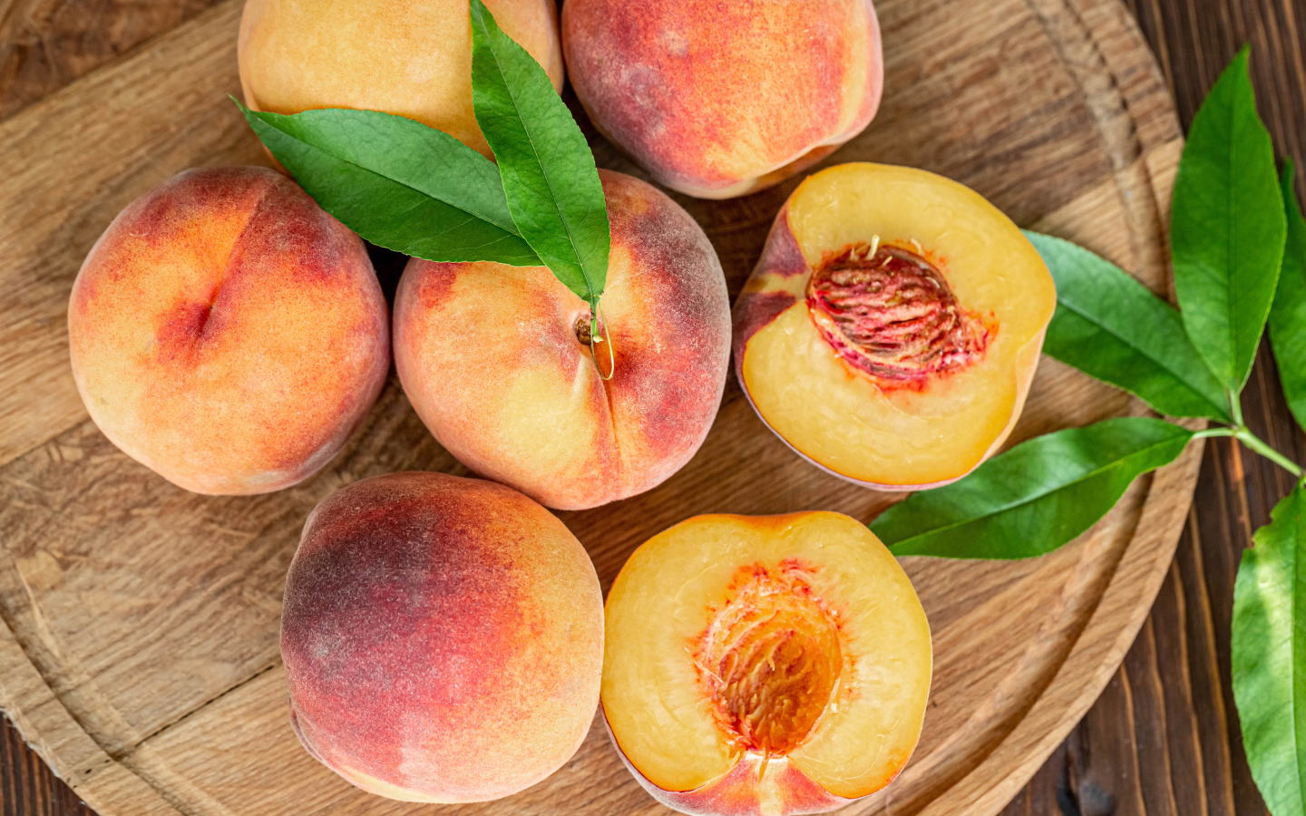 Appetizing fresh peaches on wooden board