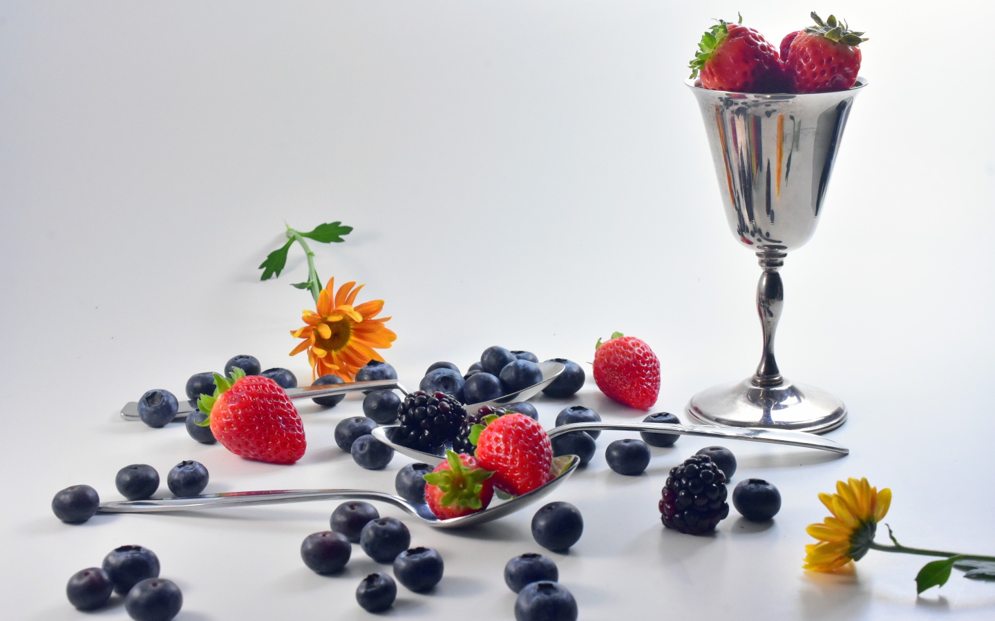 Ежевика, черника и клубника на столе с ложками