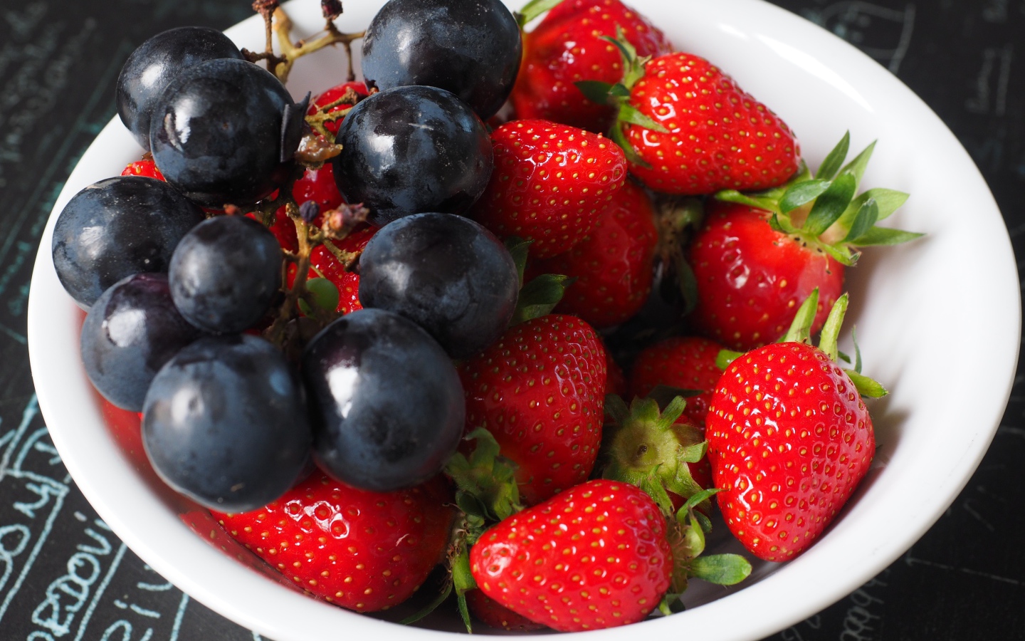 Синий виноград на тарелке с ягодами клубники 