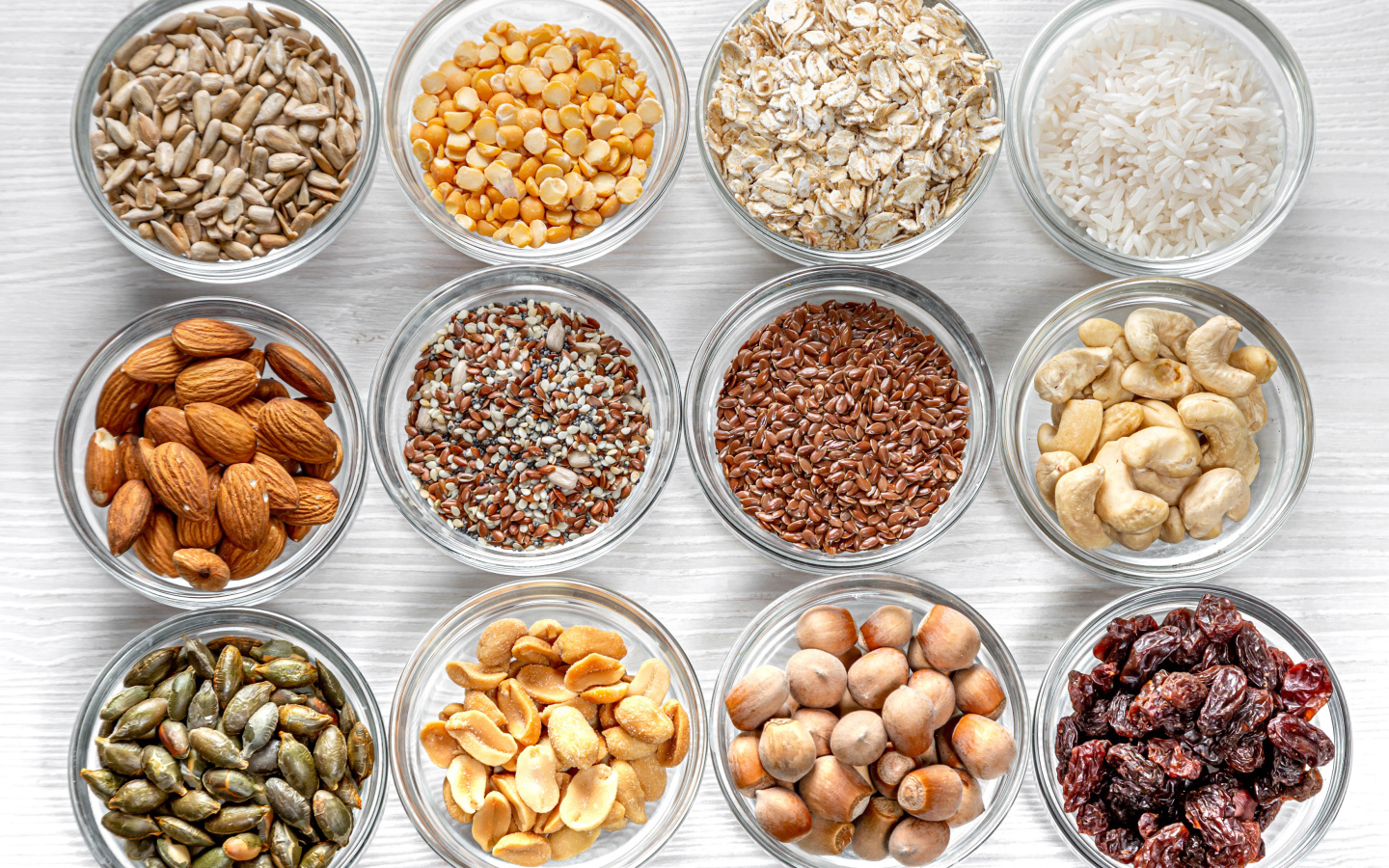 Разные виды орехов, круп и зерен в тарелках вид сверху 