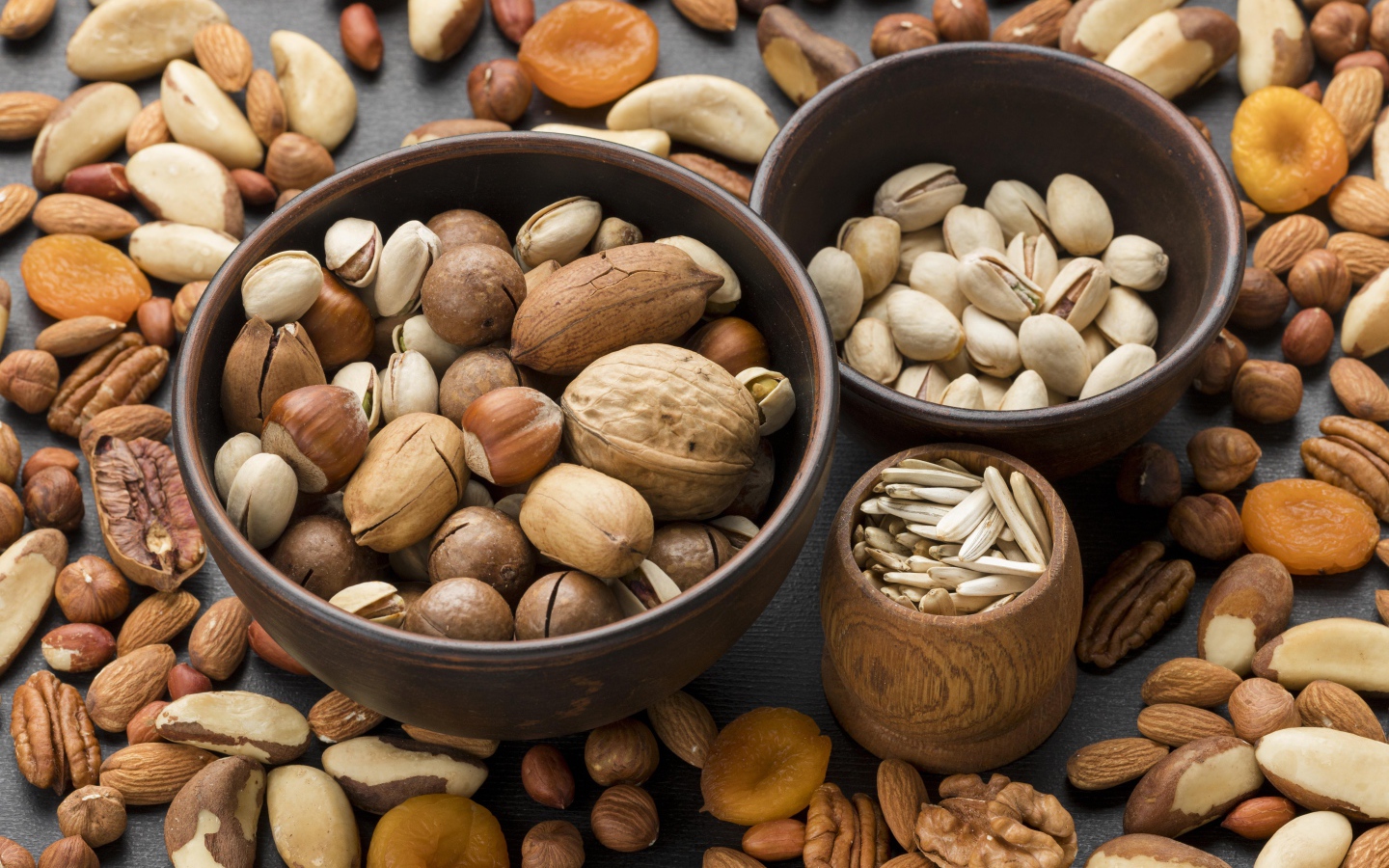 Разные виды орехов на столе в мисках 