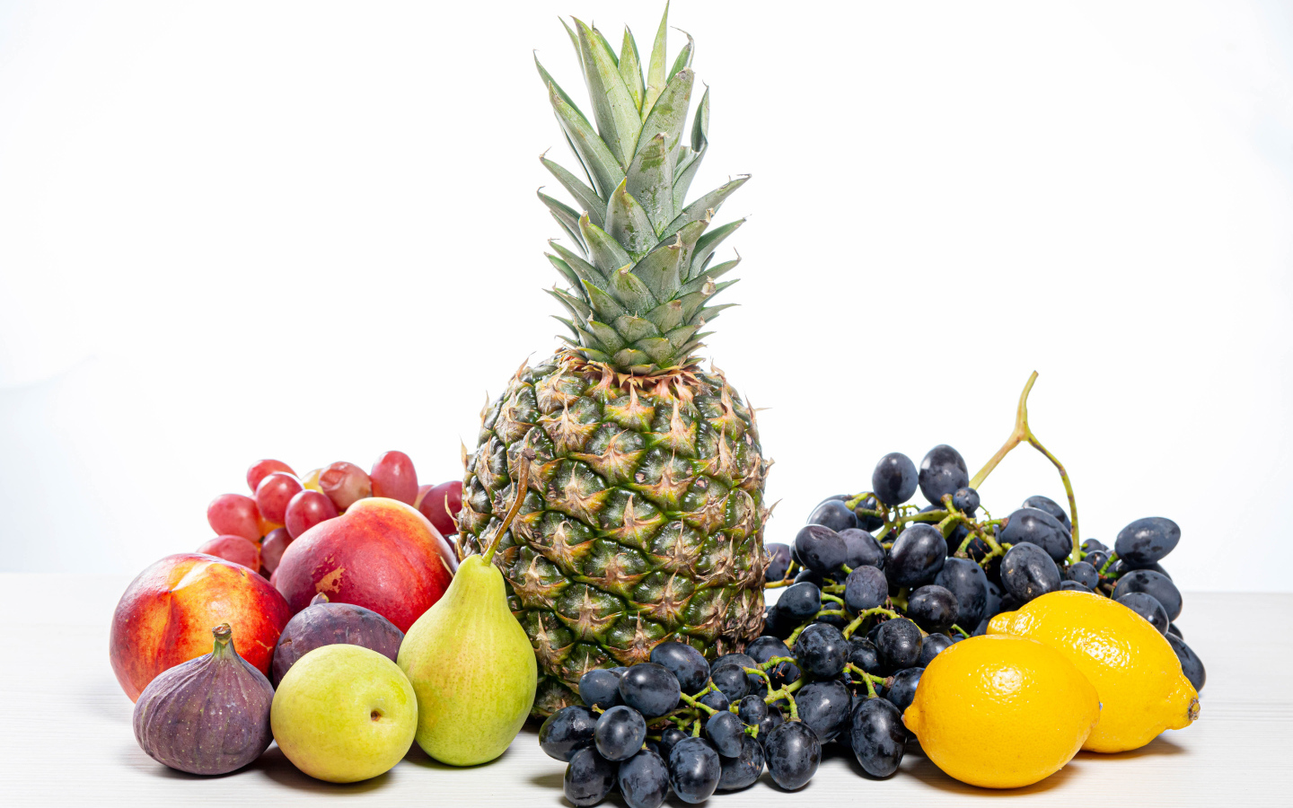 Ананас, виноград, инжир, лимон, нектарин и груши на белом фоне
