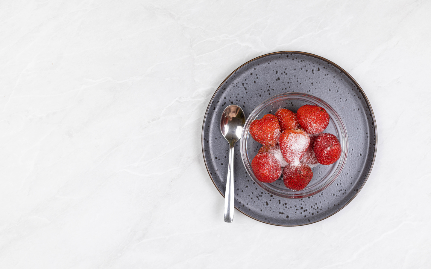 Ripe red strawberries in a bowl with sugar on a white background