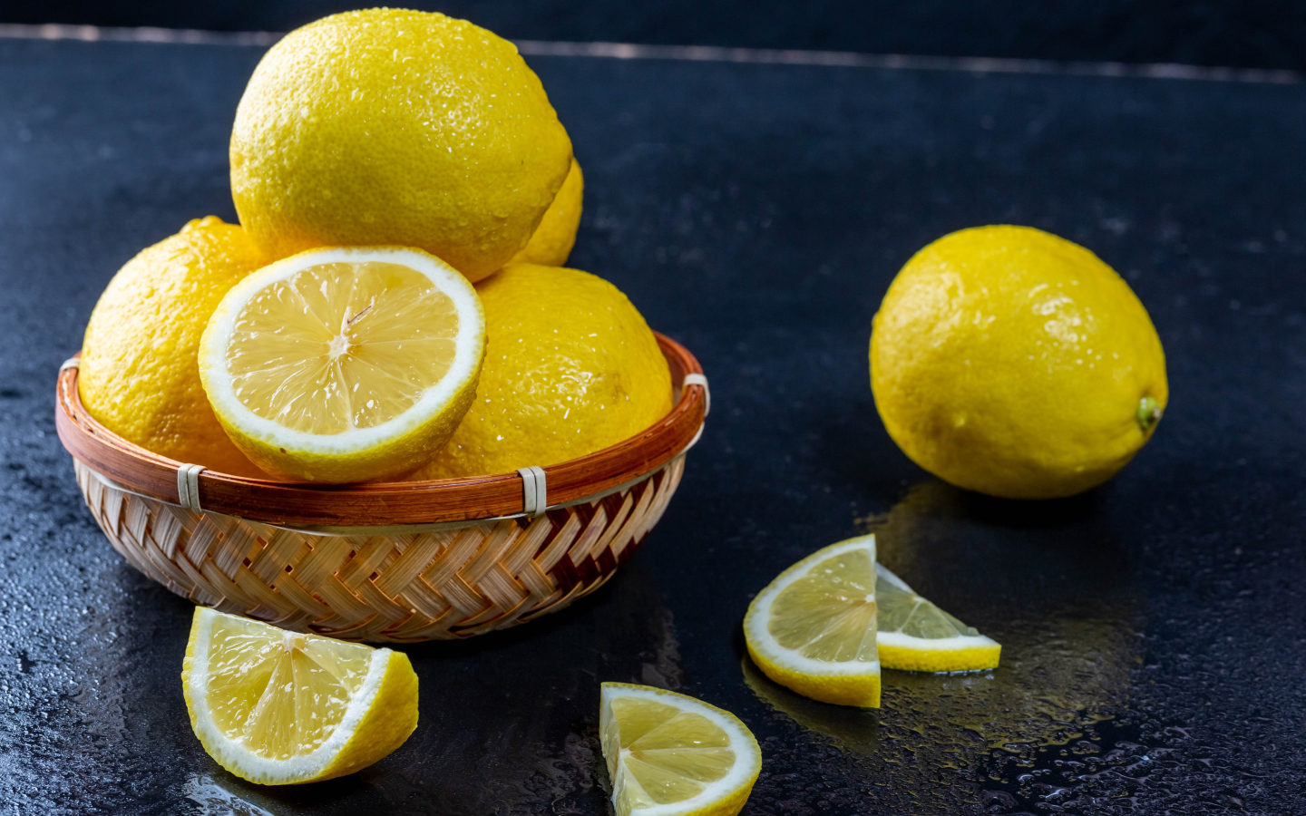 Мокрый лимон с кусочками на черном столе 