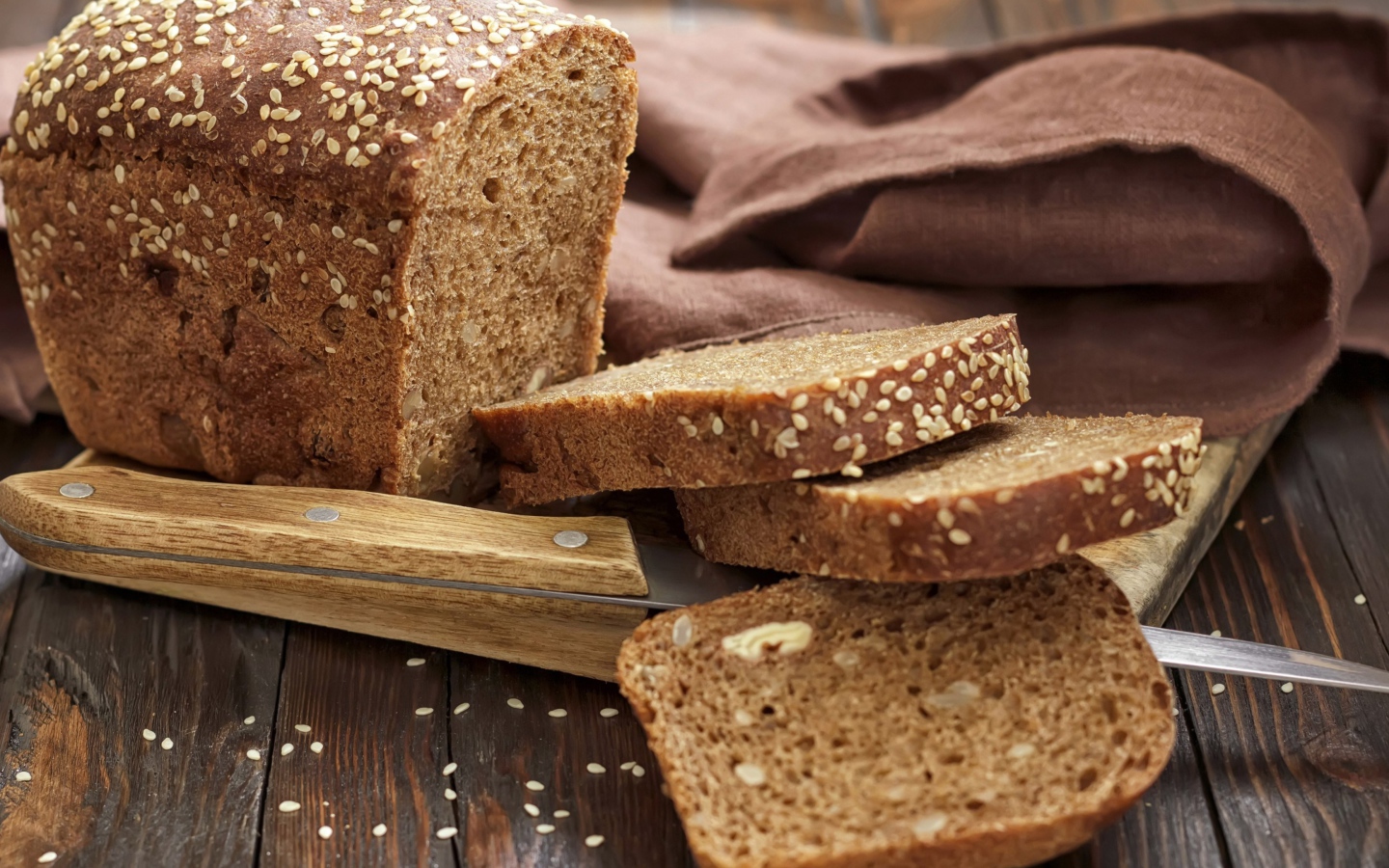 Буханка хлеба нарезанная кусочками на столе с ножом