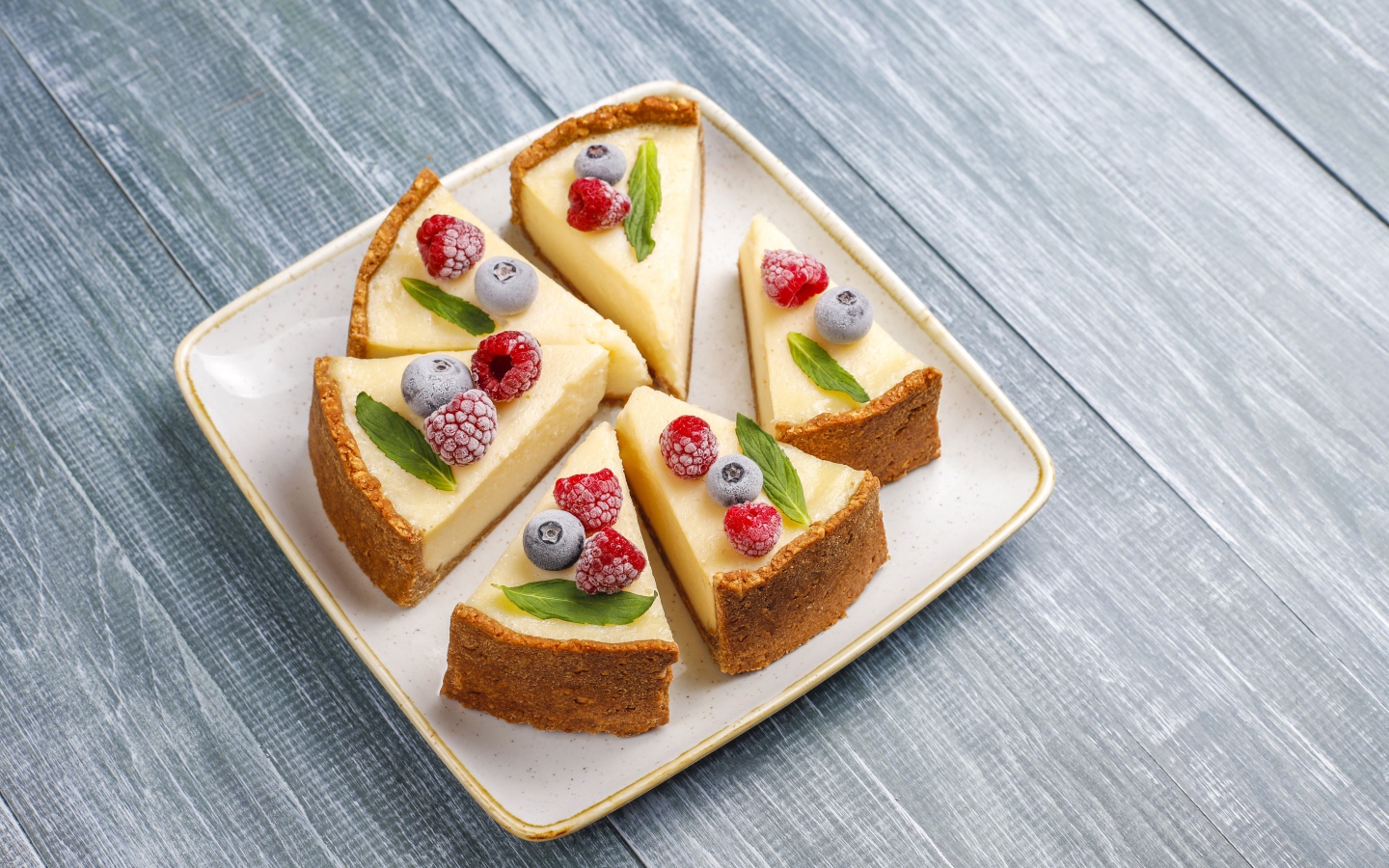 Аппетитный чизкейк с ягодами нарезан кусками на тарелке 