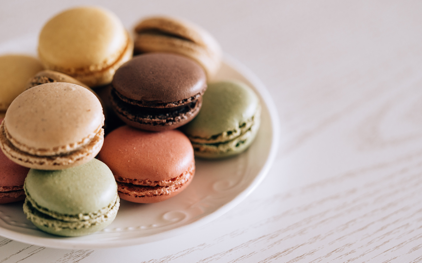 Разноцветный свежий десерт макарон на большой тарелке 