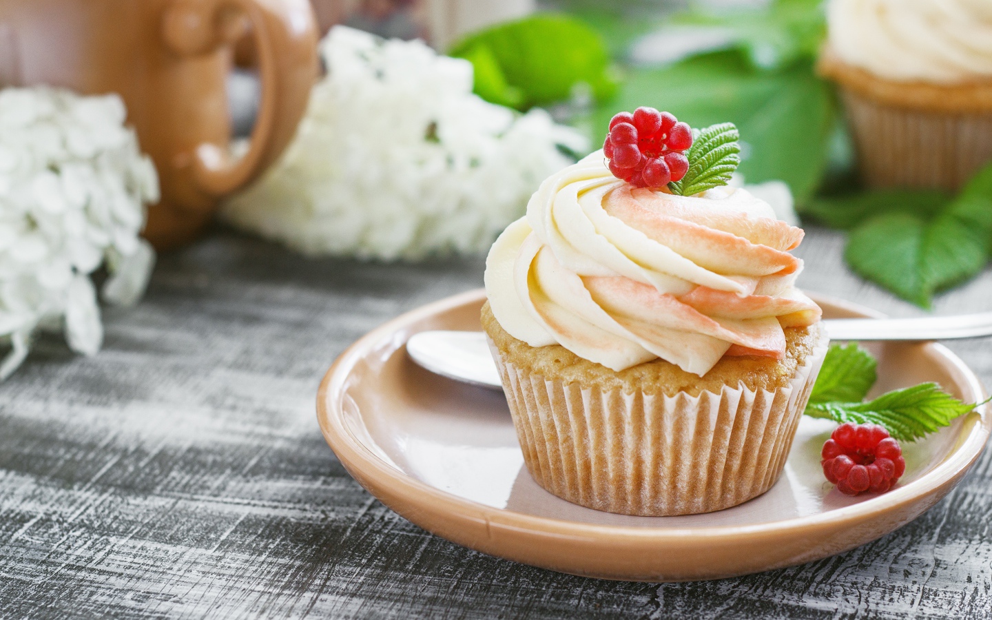 Кекс с кремом и малиной на столе