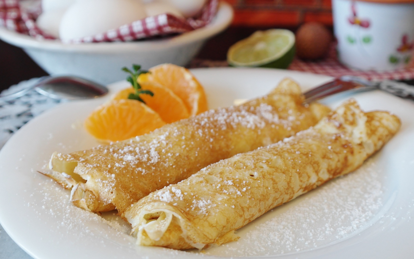 Блины с сахарной пудрой на тарелке с дольками мандарина