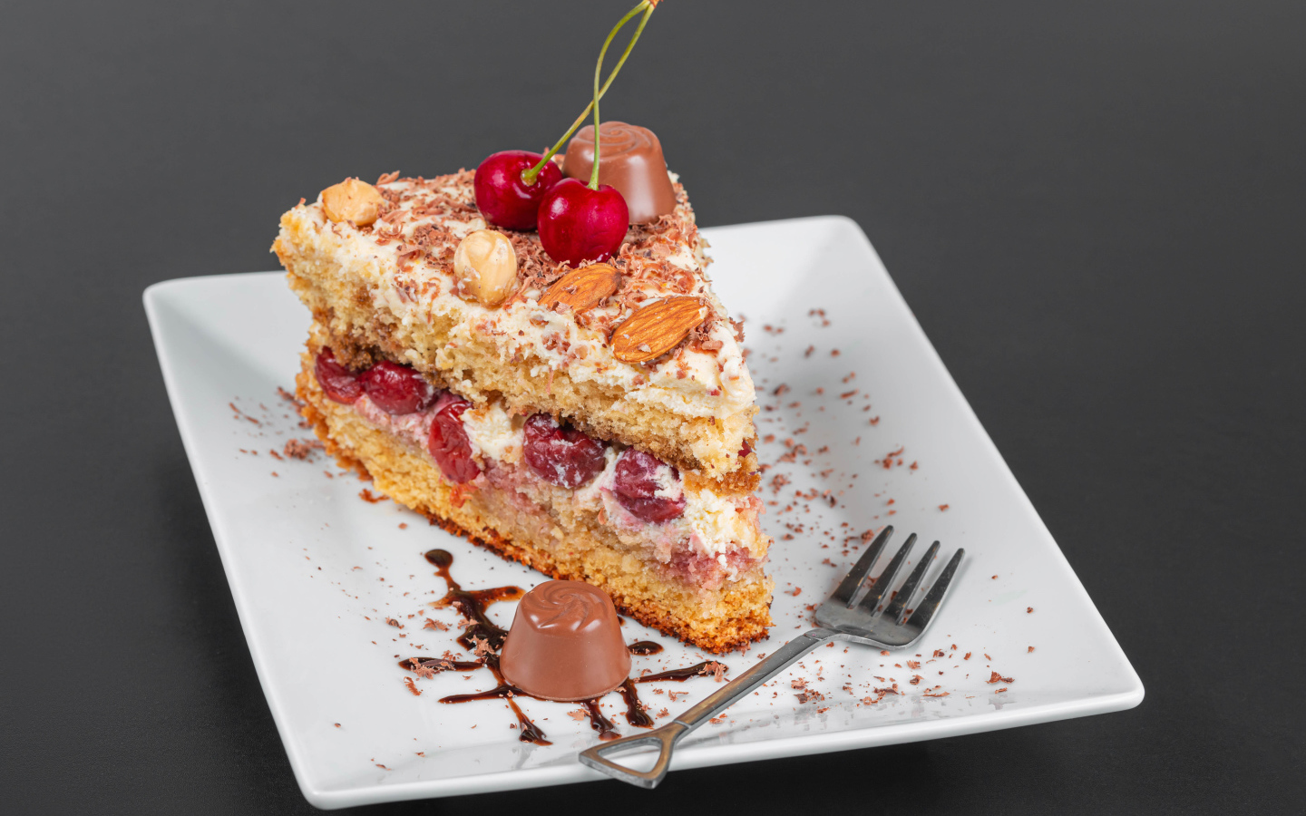 Кусок торта с ягодами вишни и миндальным орехом