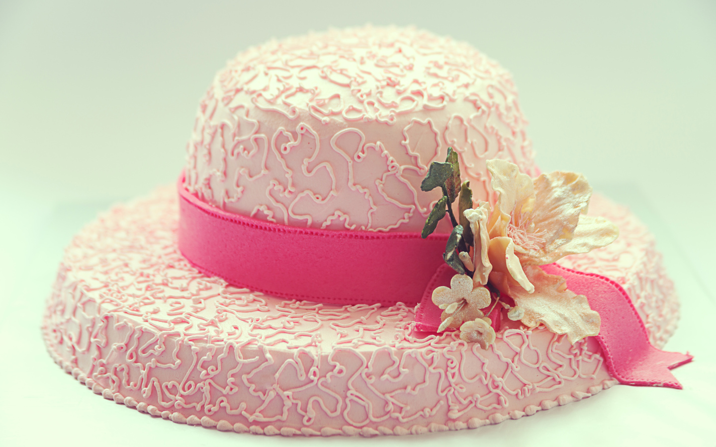 Розовый торт в виде шляпы на столе 