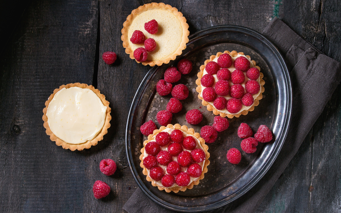 Кексы с кремом на блюде с малиной 