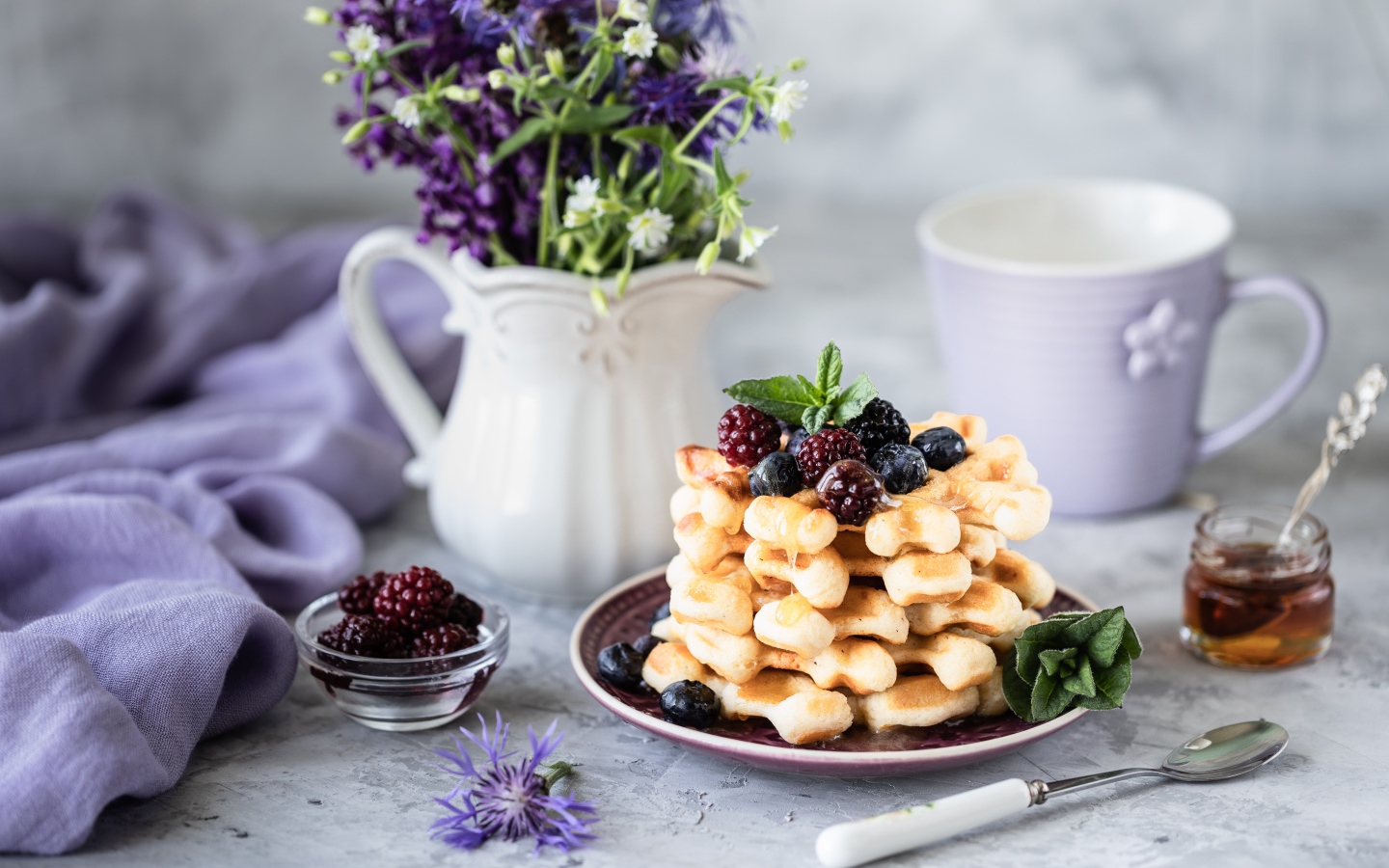Вафли с ягодами черники и ежевики на столе с букетом