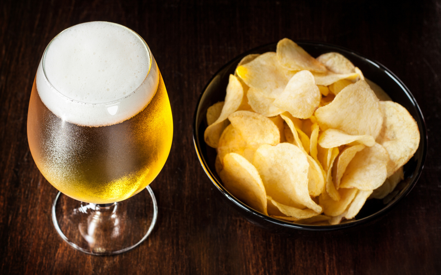 Миска с чипсами на столе с бокалом пива 