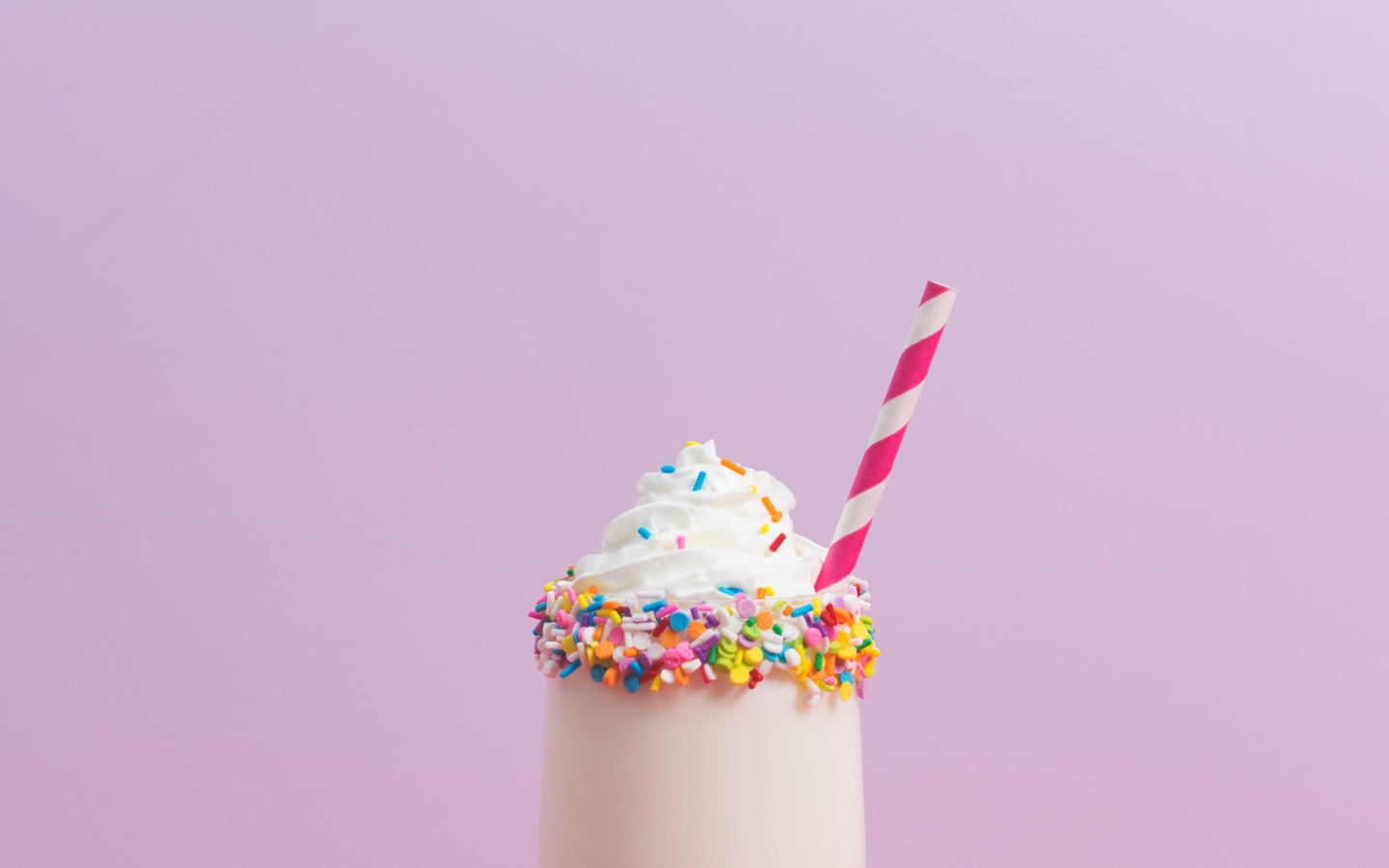 Коктейль  в стакане со взбитыми сливками на розовом фоне