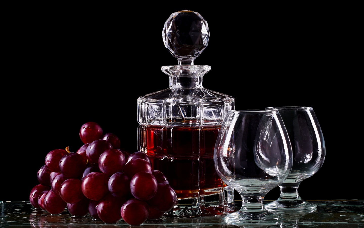 Графин с коньяком на столе с бокалами и виноградом