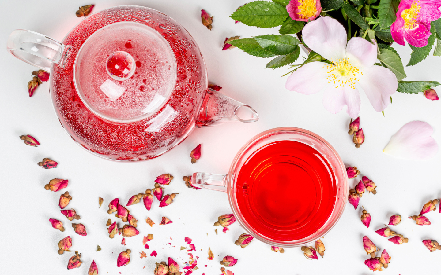 Свежий чай с шиповника в стеклянной чашке на столе с чайником