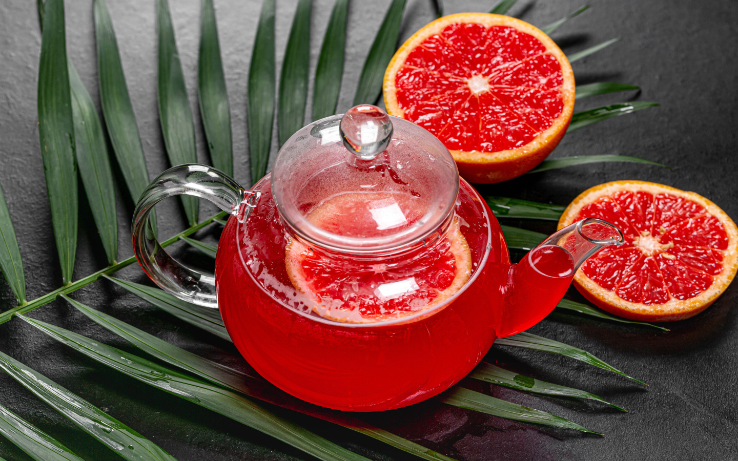 Красный чай в чайнике на столе в грейпфрутом и листьями