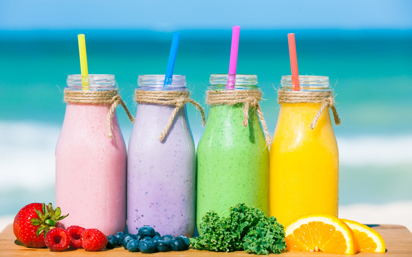 Три бутылочки со смузи на столе на пляже