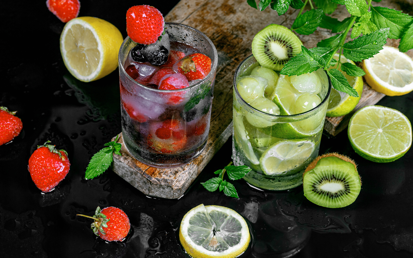 Два стакана мохито на столе с мятой, лимоном и клубникой 