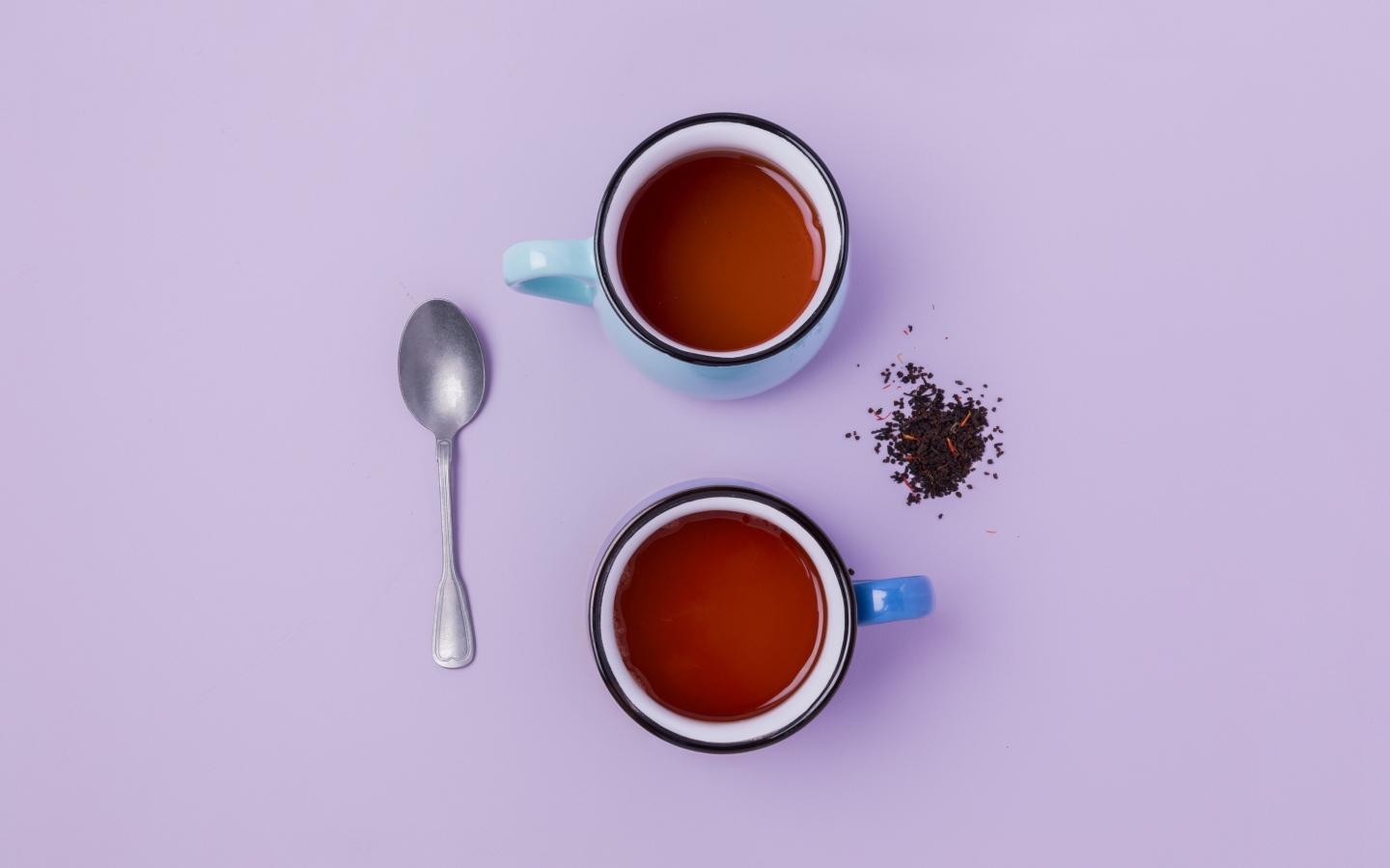 Две железные чашки чая на сиреневом фоне с ложкой