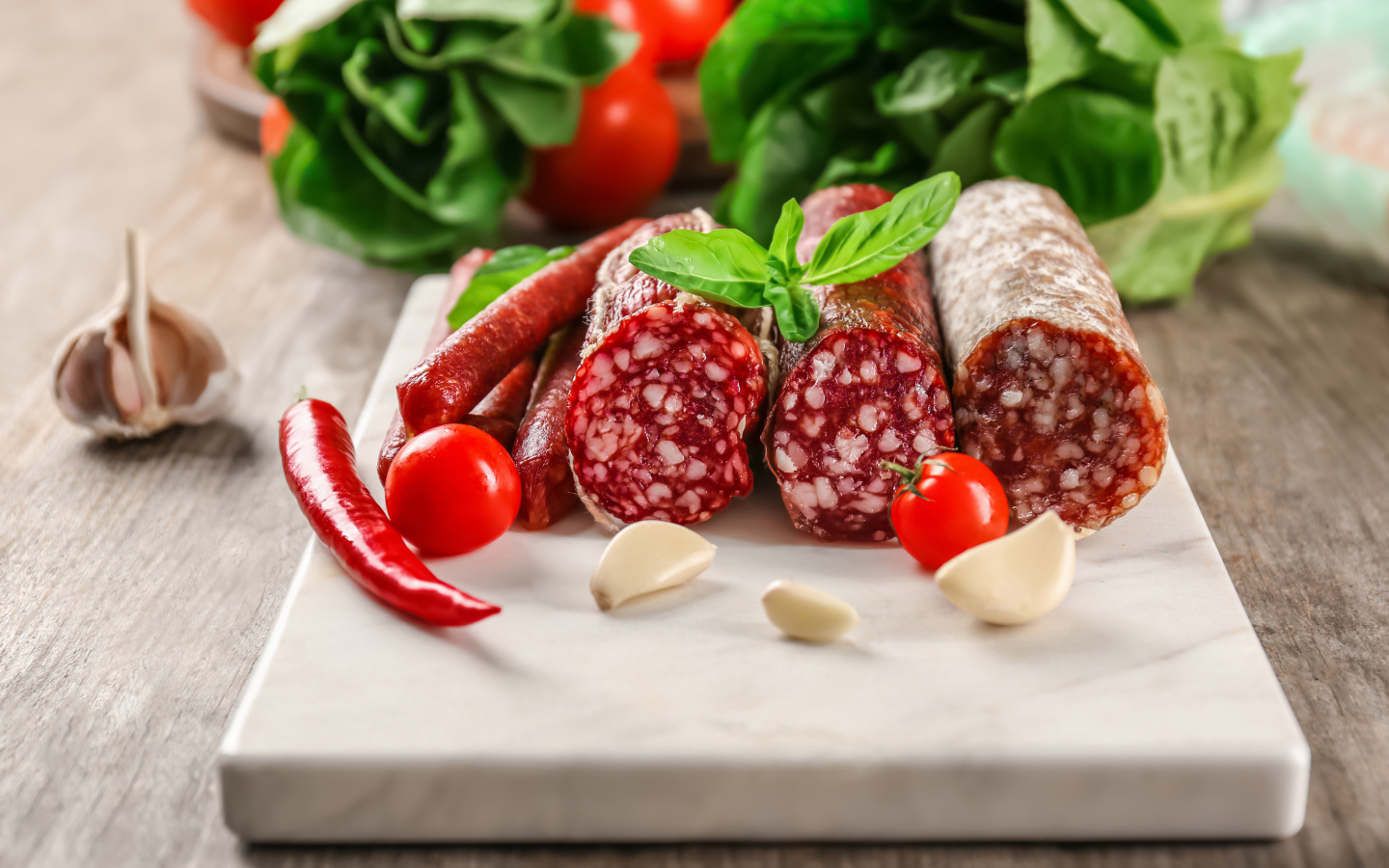 Вкусные колбасные изделия на столе с овощами