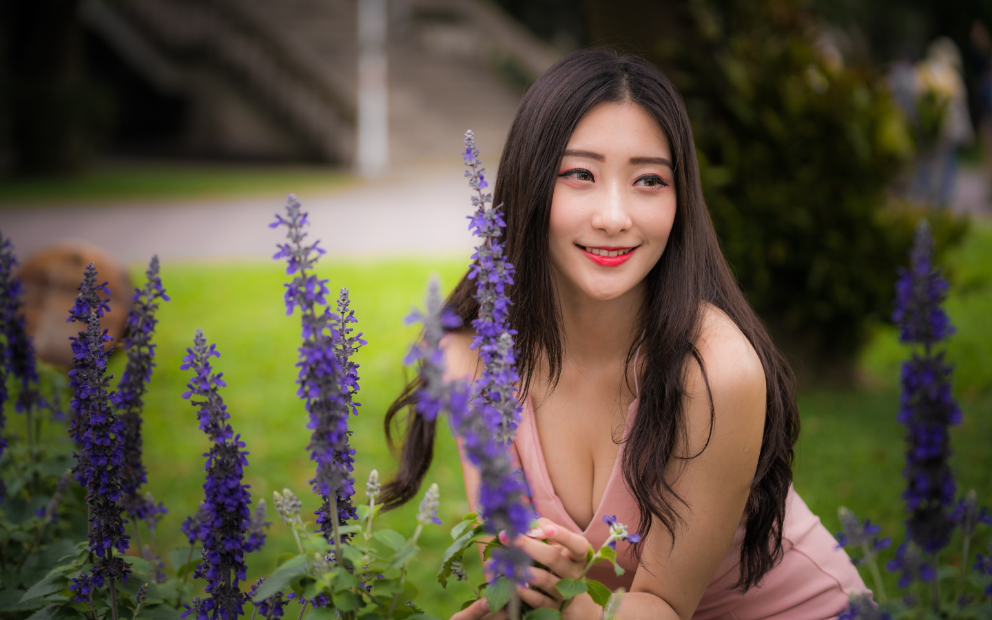 Улыбающаяся азиатка стоит у синих цветов 