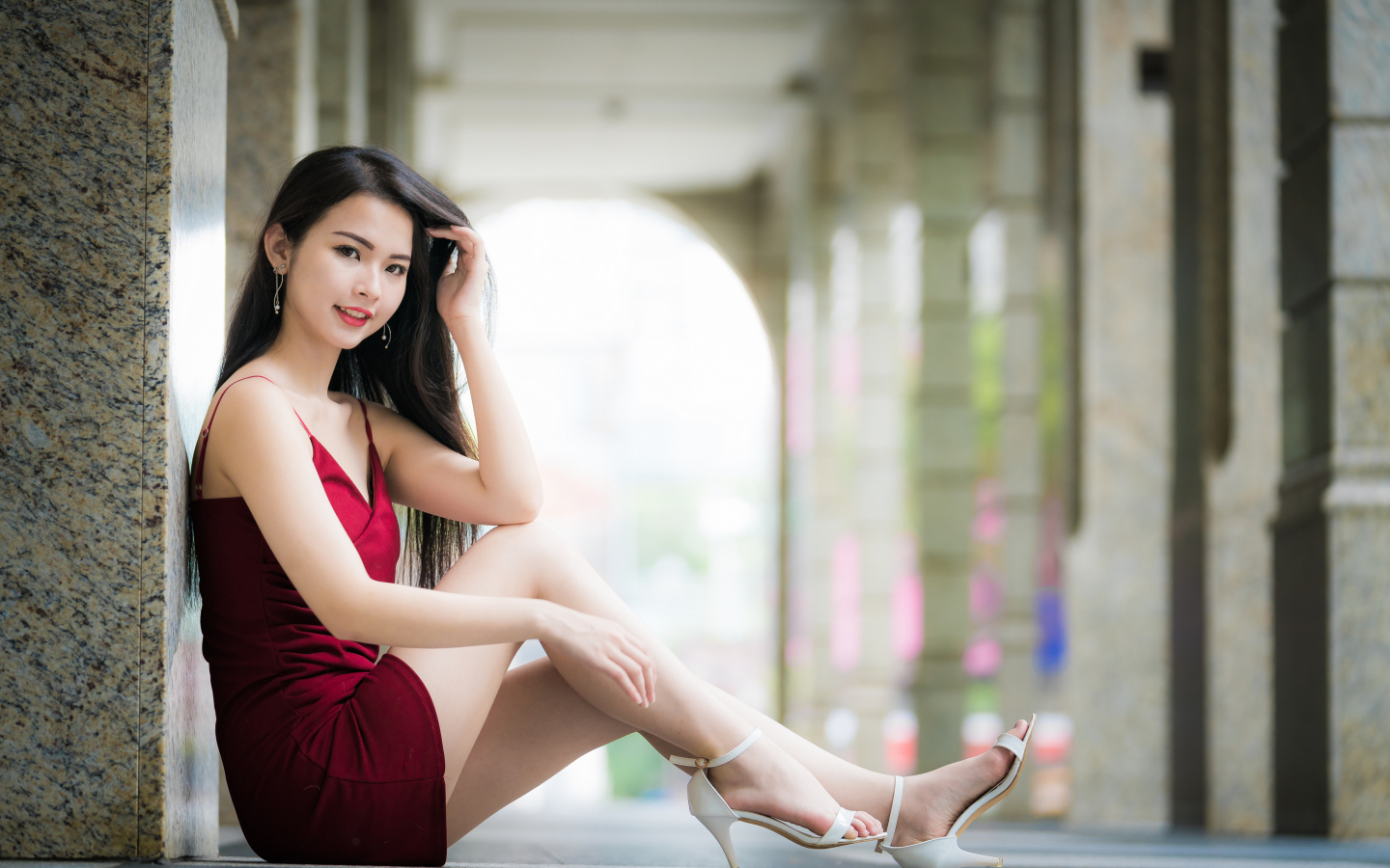 Девушка азиатка в красном платье сидит на полу
