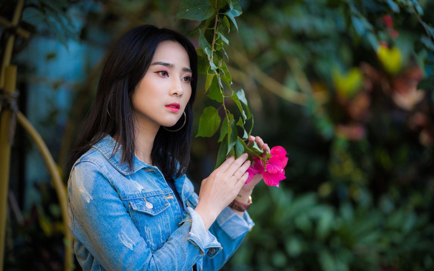 Девушка азиатка в джинсовой куртке в парке