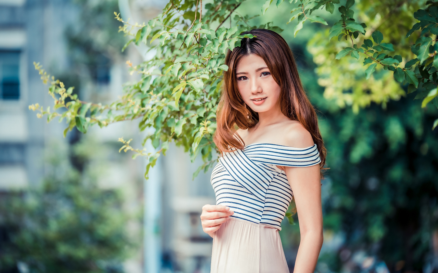 Девушка азиатка стоит под деревом в парке 