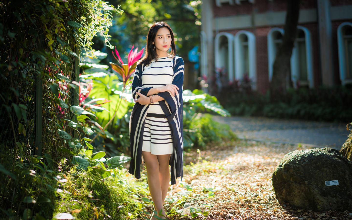 Девушка азиатка идет по улице у забора