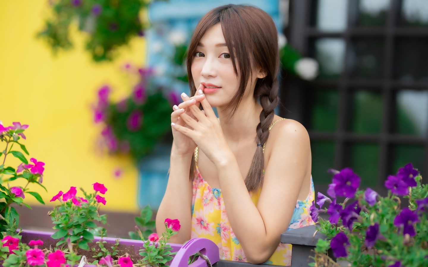 Красивая девушка Азиатка у цветов петунии