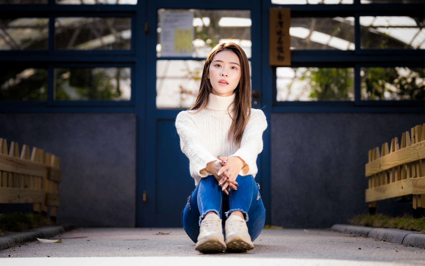 Красивая азиатка в синих джинсах сидит на земле