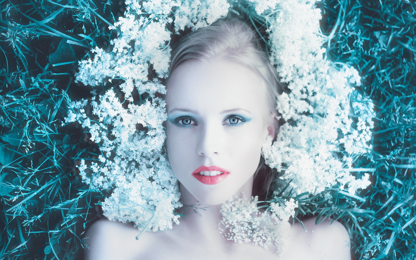 Красивая голубоглазая девушка на траве с белыми цветами