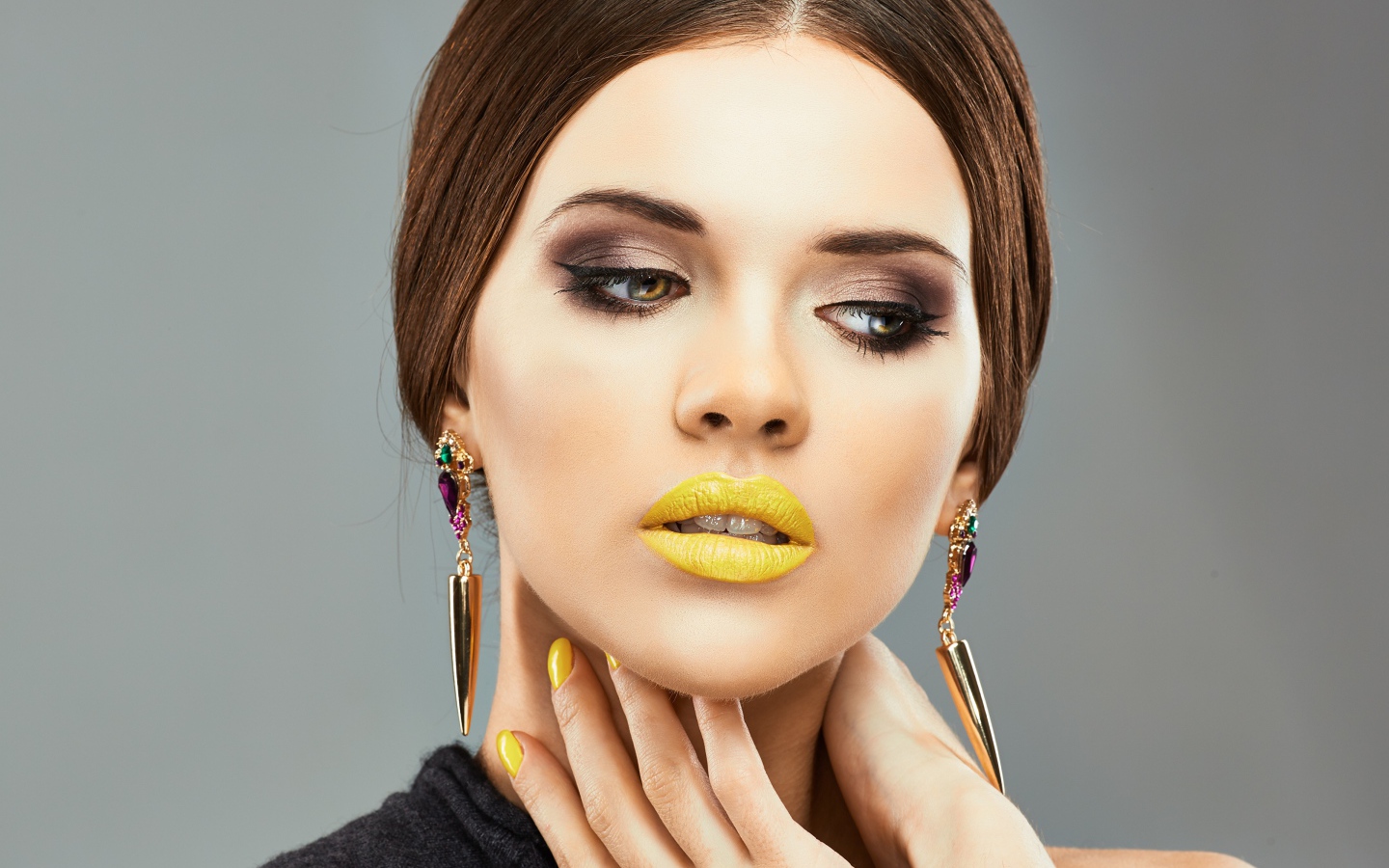 Красивая девушка с дорогими серьгами в ушах на сером фоне