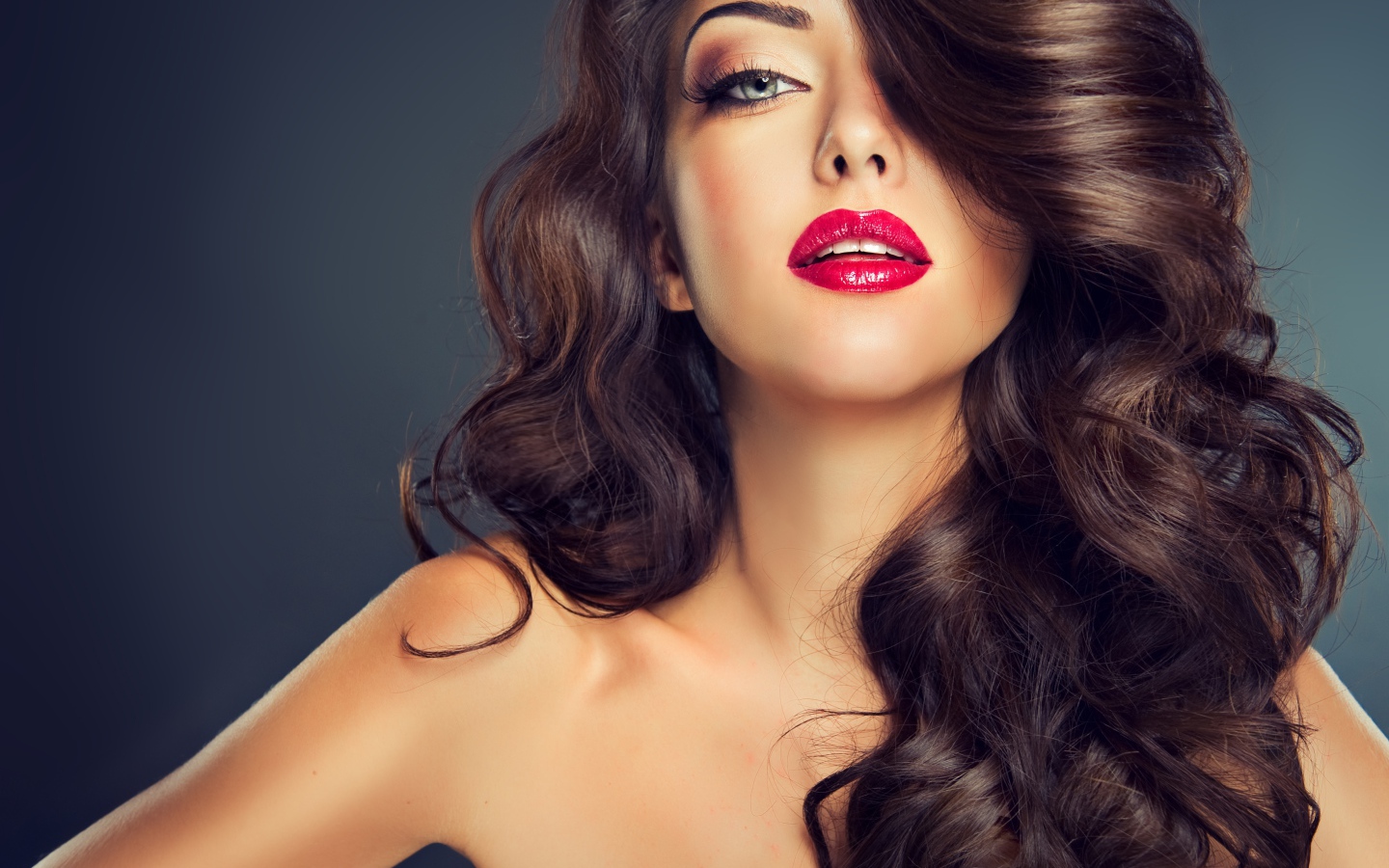 Beautiful girl with long hair and red lips on a gray background