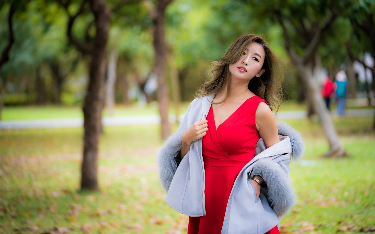 Яркая девушка азиатка в красном платье в парке