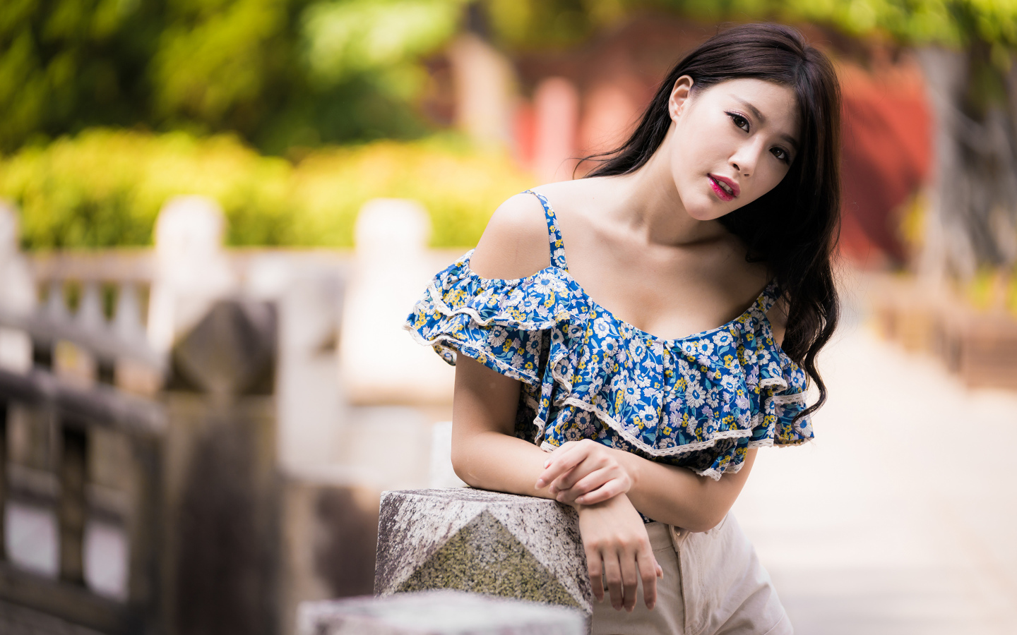 Кареглазая азиатка в яркой кофте в парке 