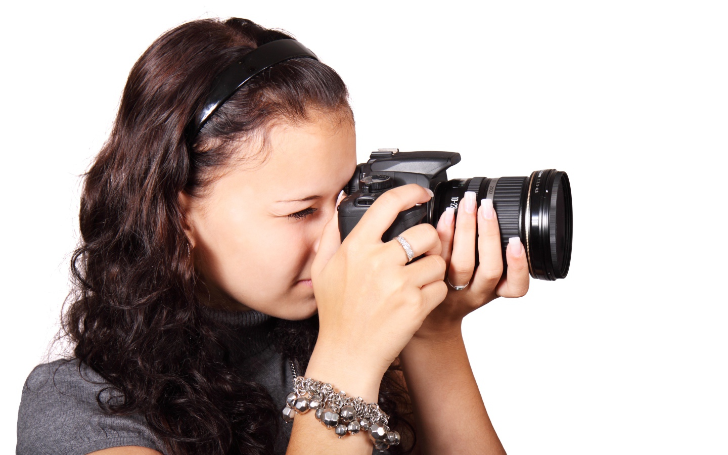 Молодая девушка шатенка с фотоаппаратом в руках на белом фоне