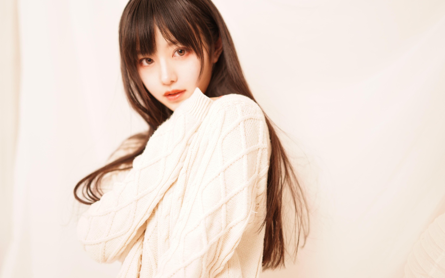 Милая азиатка в белом свитере на розовом фоне