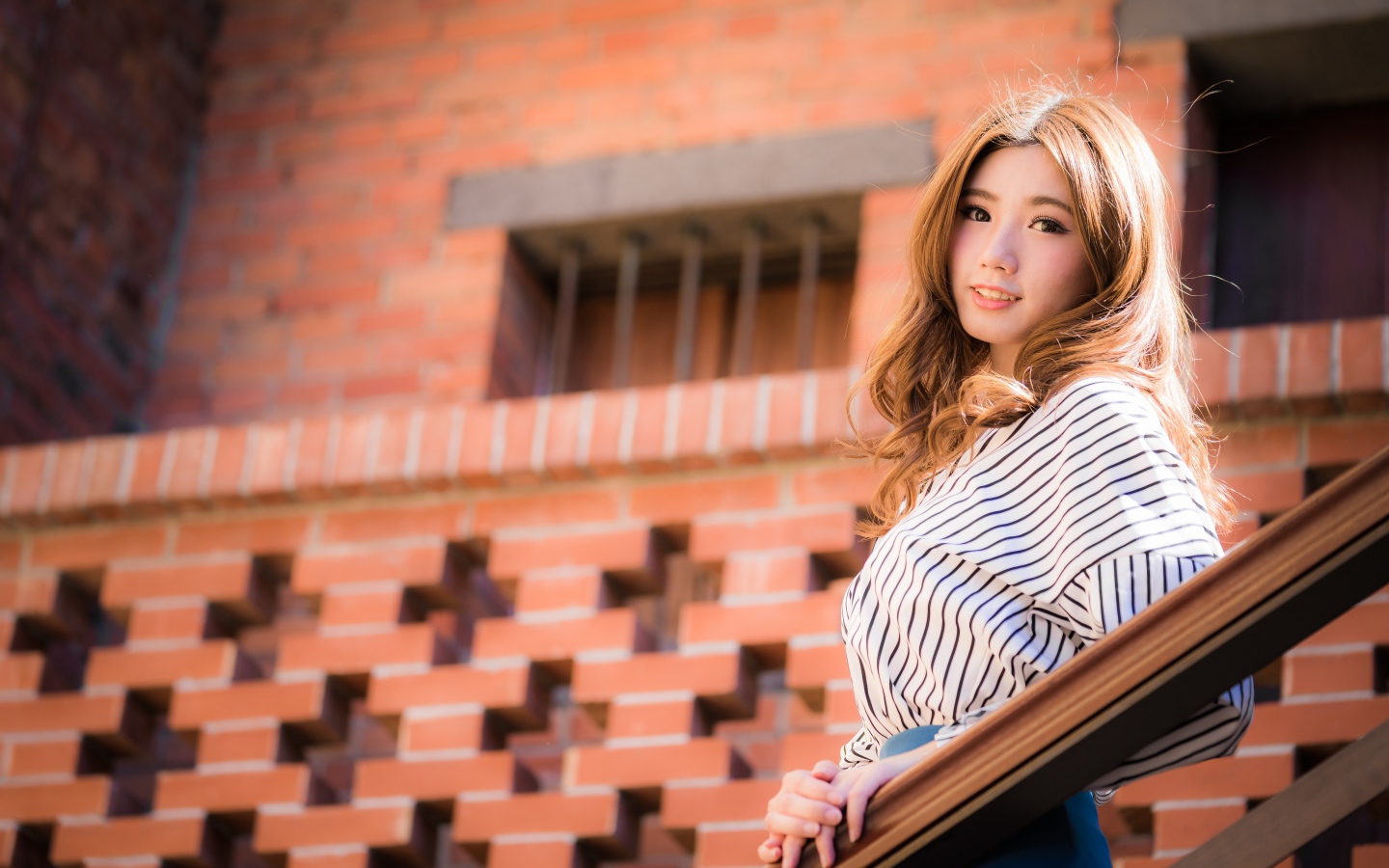 Милая девушка в полосатой рубашке стоит на ступеньках 