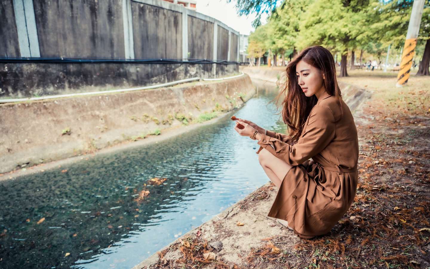 Мечтательная девушка азиатка сидит у воды