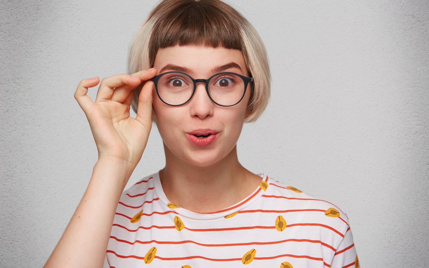 Девушка с короткой стрижкой поправляет очки 