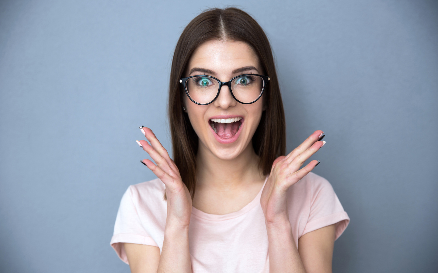 Радостная девушка в очках на сером фоне