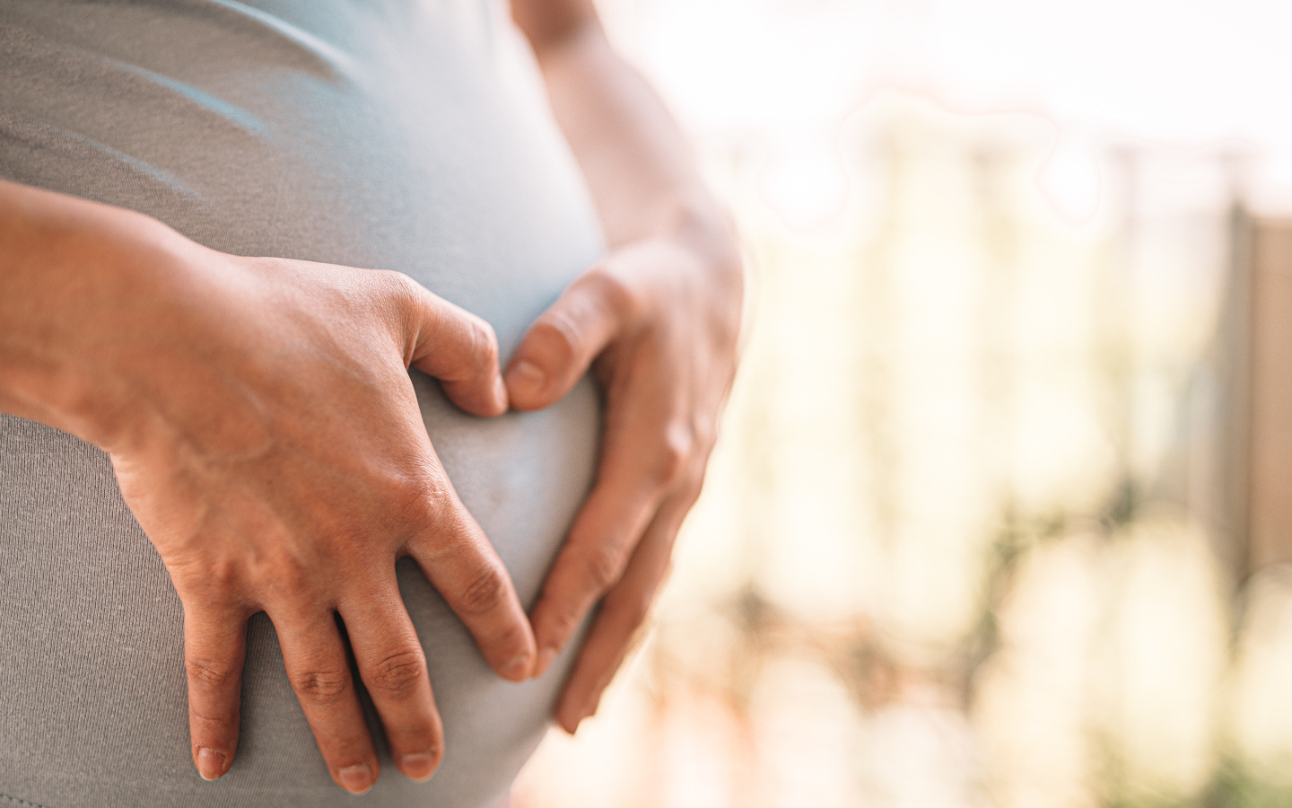 Беременная женщина держит руки на животе 