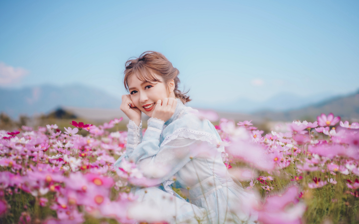 Улыбающаяся девушка азиатка на поле с цветами космеи 