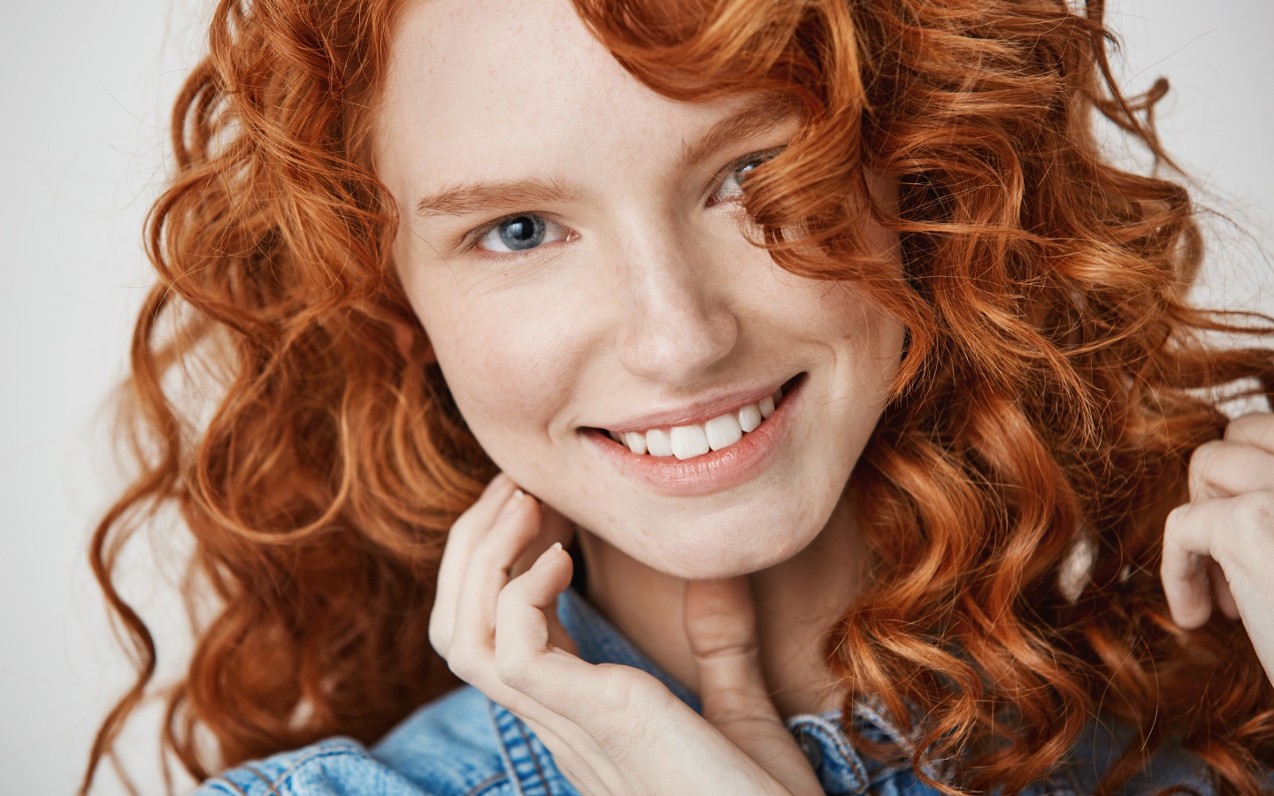 Улыбающаяся голубоглазая рыжеволосая девушка в джинсовой куртке 