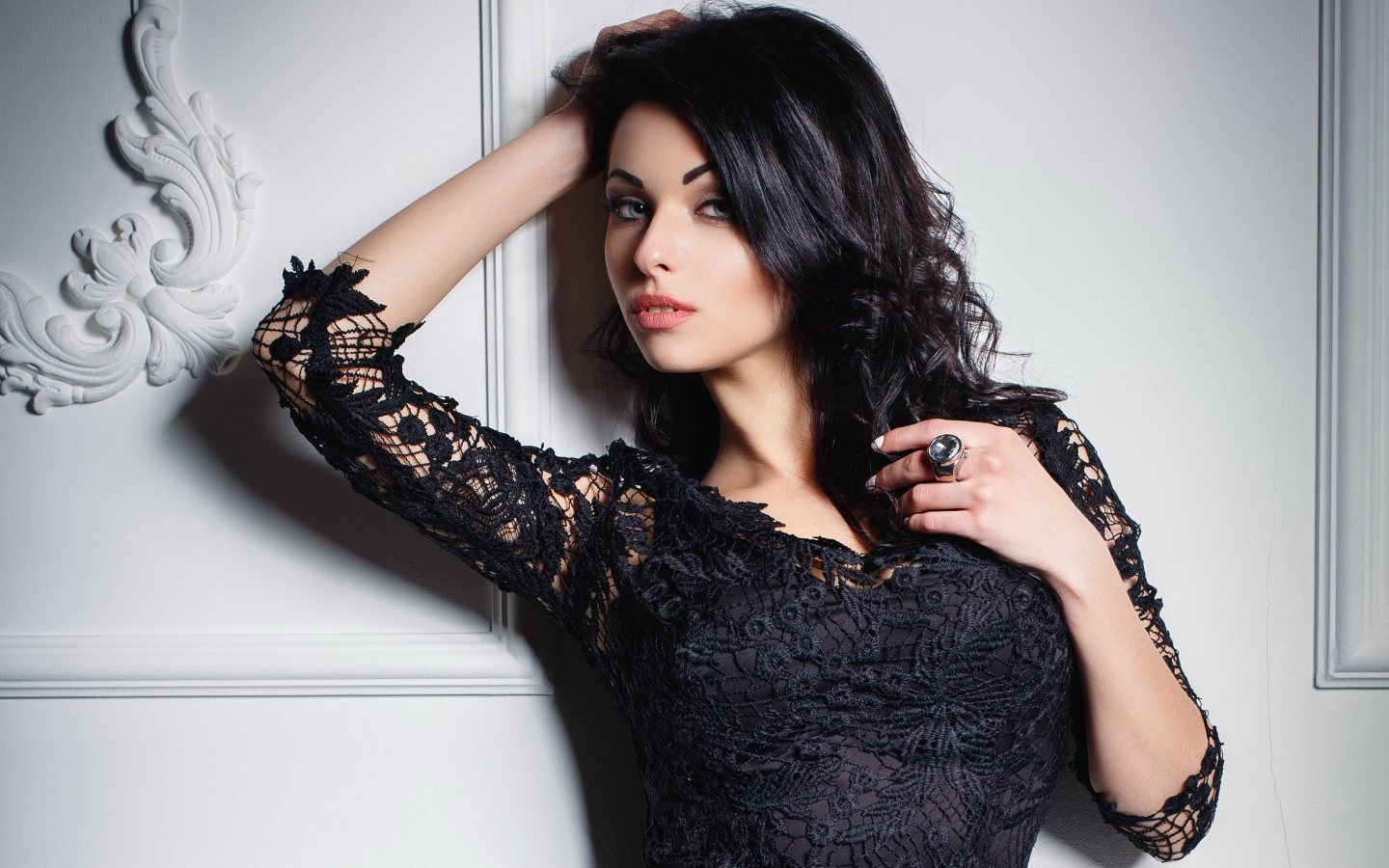 Эффектная брюнетка в черном платье у стены